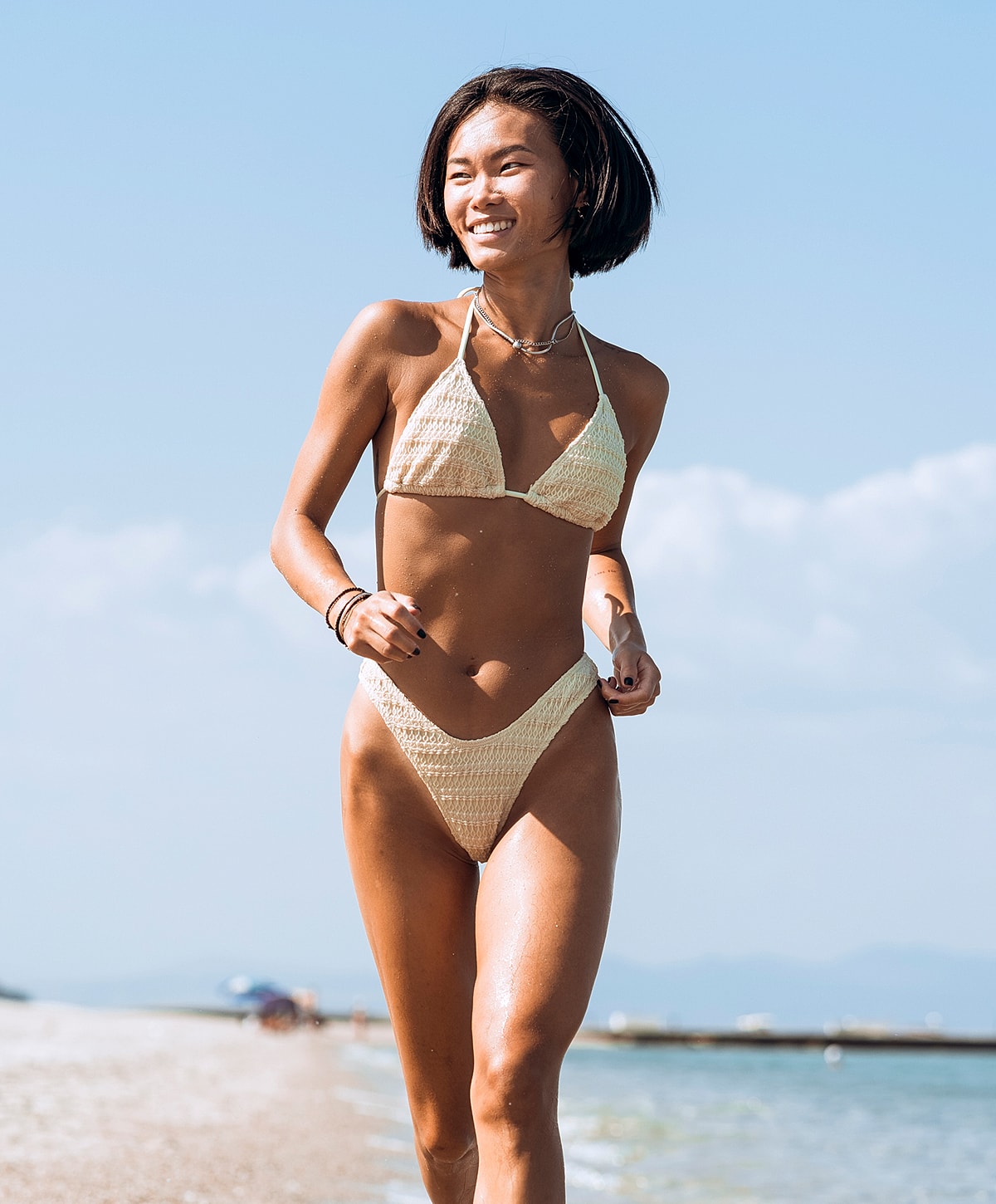 Woman running on beach in swimwear.