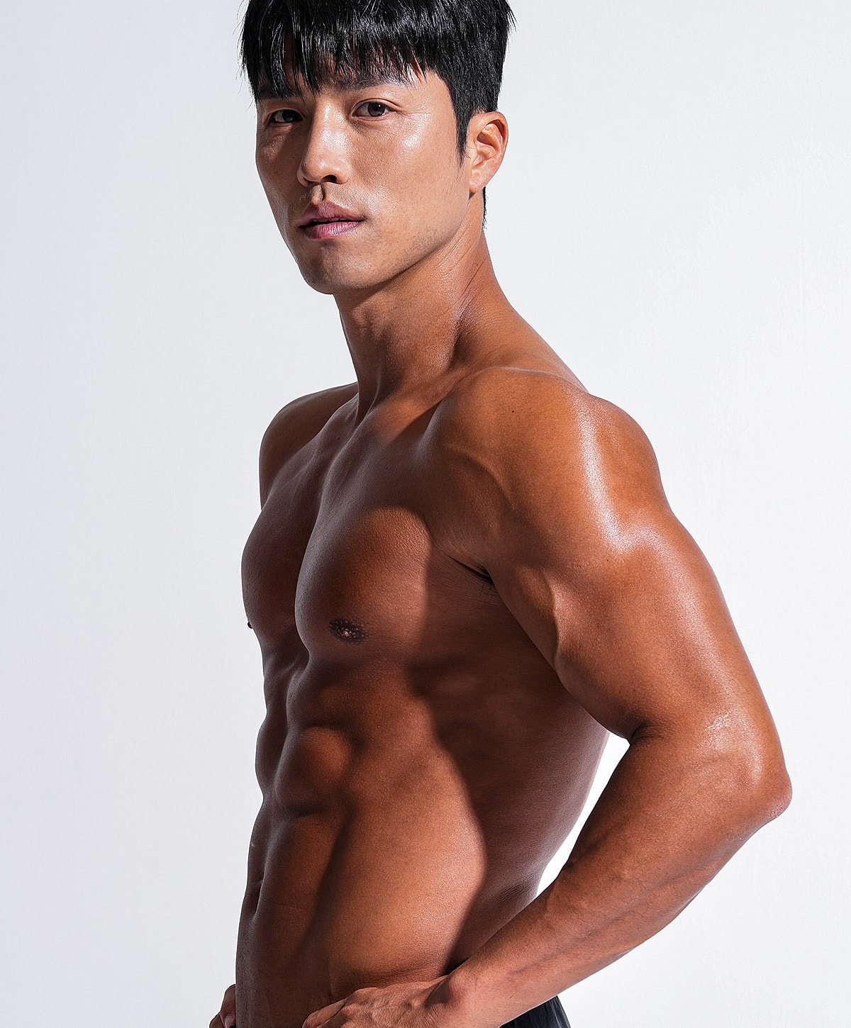 Man with athletic build posing against white background.