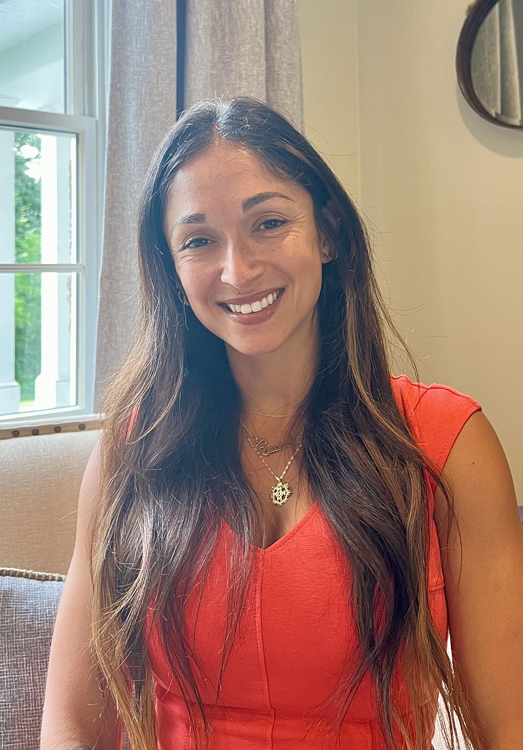 Smiling person in coral dress indoors.