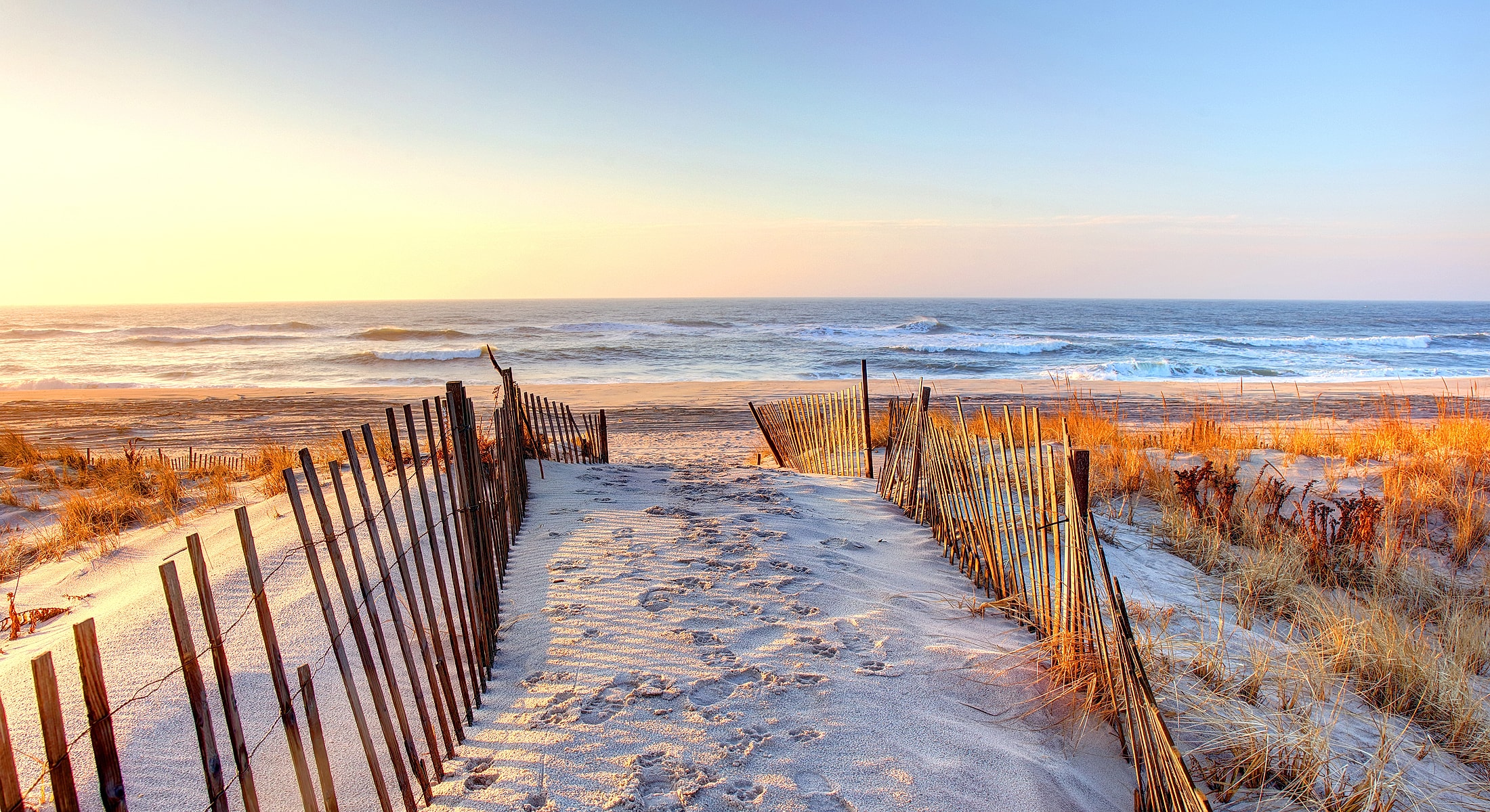 Pathway leading to a serene beach at sunset.